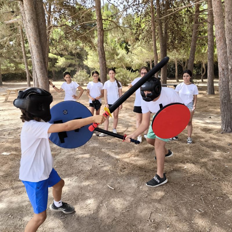 Two participants in protective gear engaging in a thrilling sword fighting duel, showcasing their skills and precision.