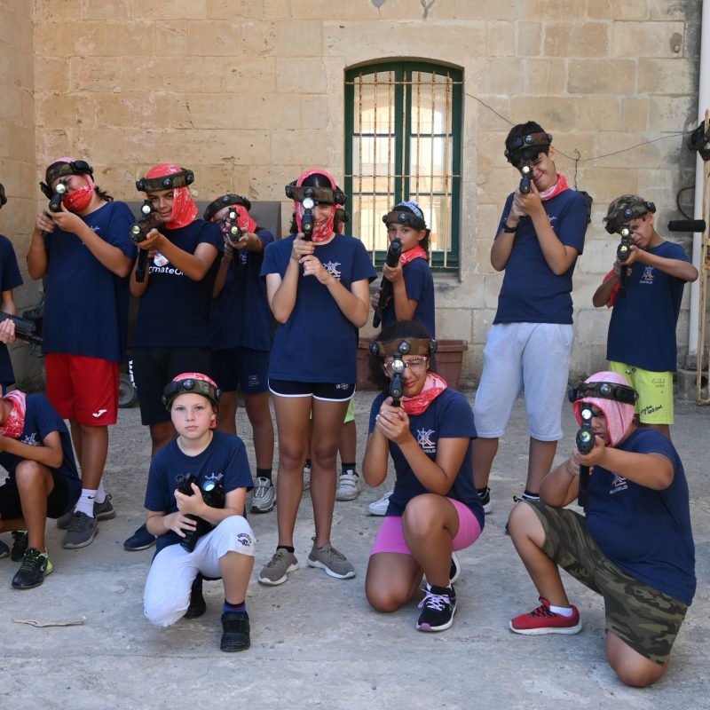 Players enjoying a BattleMAXX Laser Tag match in an open outdoor area, aiming and taking cover during the game.