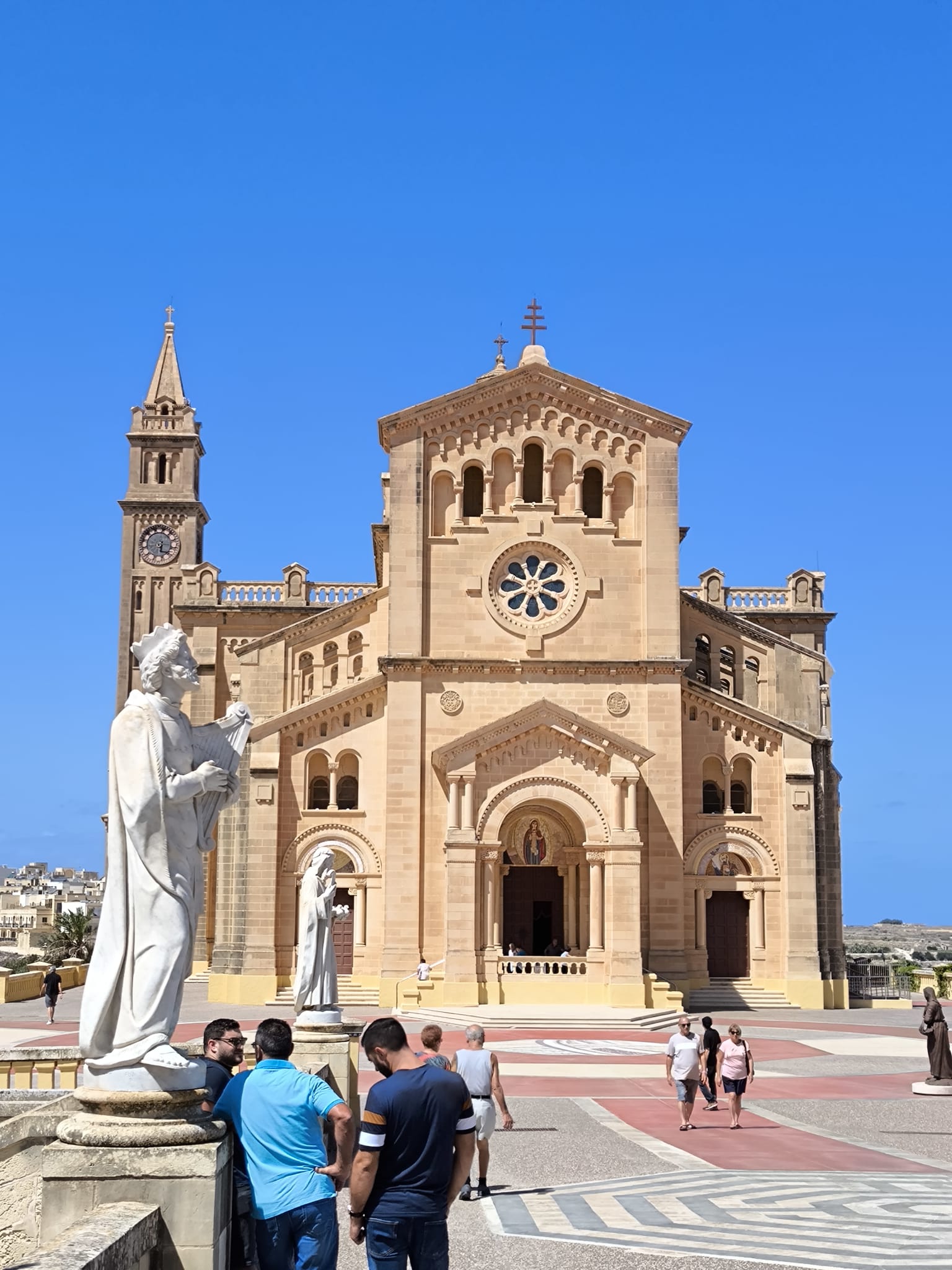 A group of people exploring the Ta' Pinu Basilica in Gozo, admiring the architecture and surrounding landscape.